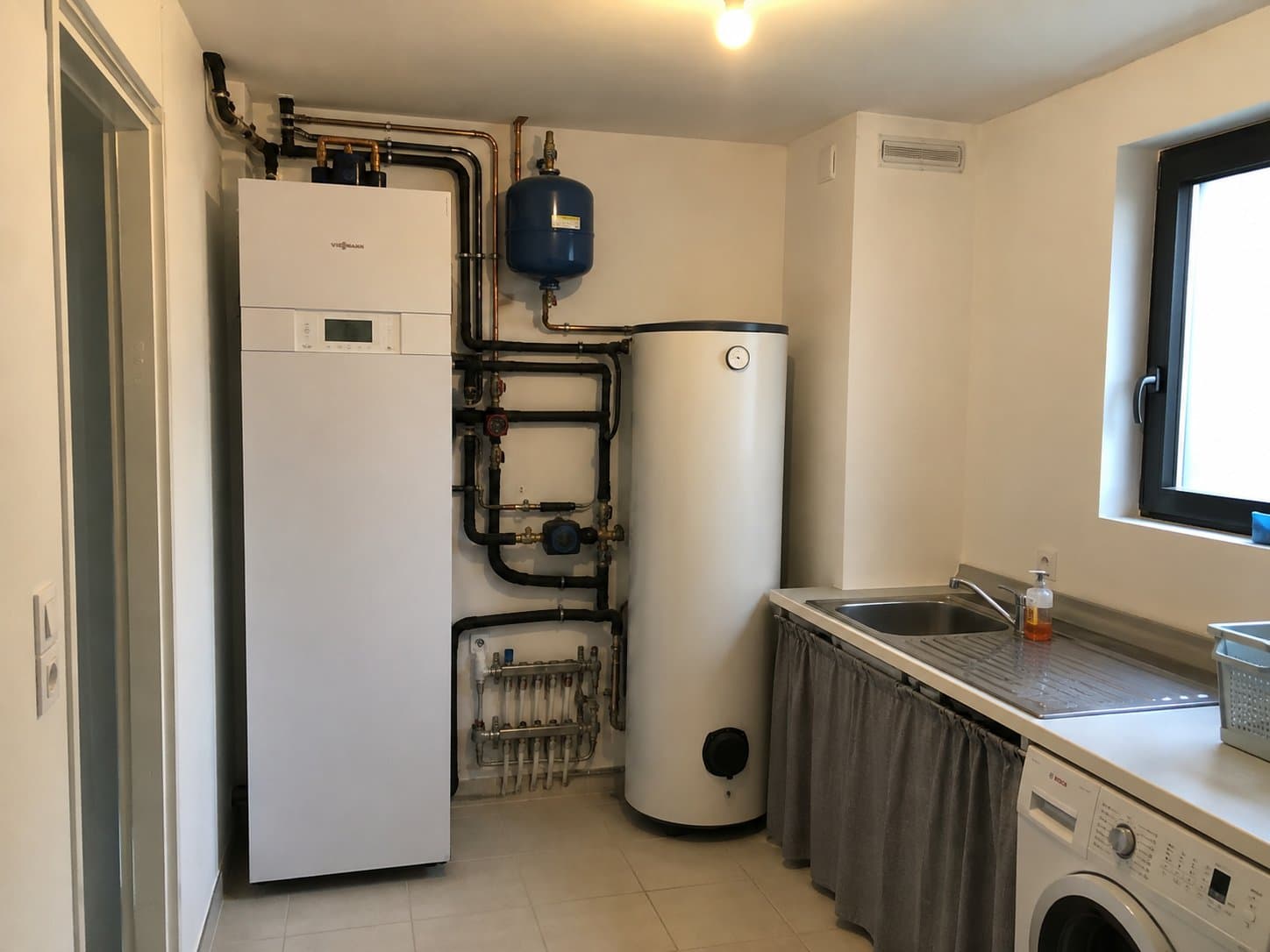 Groupe intérieur de pompe à chaleur air/eau et ballon tampon installés en buanderie
